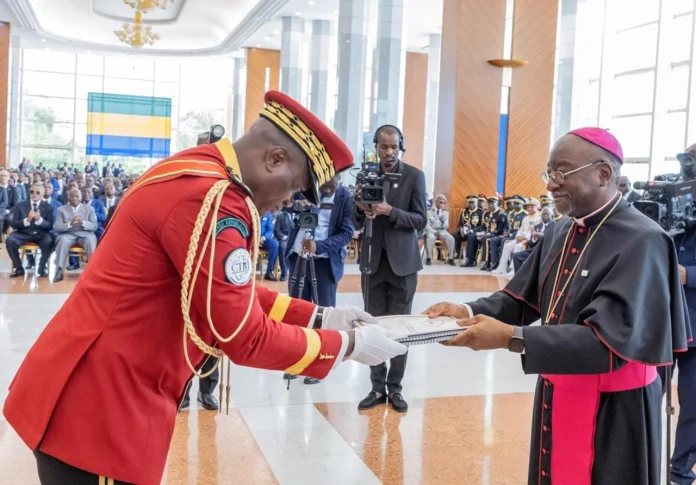 Le PrÃ©sident de la Transition, GÃ©nÃ©ral Brice Clotaire Oligui Nguema, recevant le rapport du dialogue national inclusif des mains de l'archevÃªque de Libreville Monseigneur Jean Patrick Iba Ba prÃ©sident du dialogue. Â© mediapostegabon